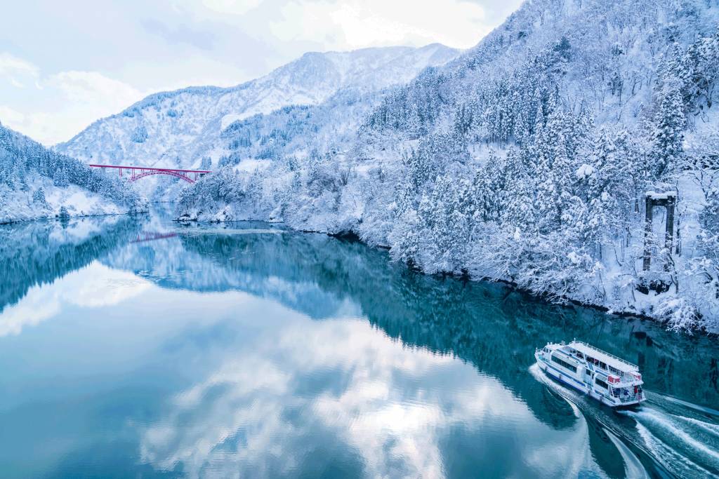 富山 遊覽船在銀白峽谷中慢慢游弋，遊客可以舒舒服服坐在暖氣船艙內欣賞冰封白色世界下的赤紅色利賀大橋美景。